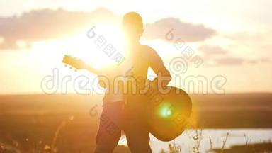 戴着<strong>圆眼镜</strong>的男孩在日落时分的田野里弹吉他